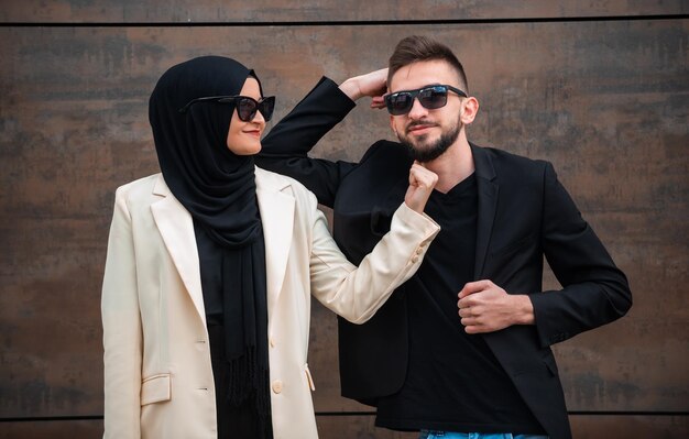 Een jonge man en vrouw staan samen voor een houten wand.