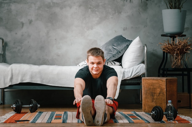 Een jonge man gaat thuis sporten, online trainen vanaf de telefoon