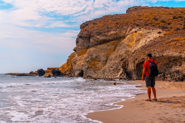 Een jonge man geniet van de prachtige rotsen aan de kustlijn bij Cala de la Media Luna in het natuurpark Cabo de Gata, Nijar, Andalusië. Spanje, Middellandse Zee