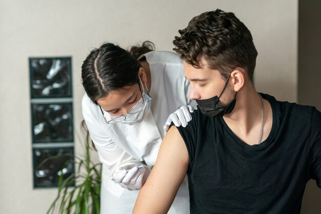 Een jonge man heeft een injectie in de schouder gekregen Vaccinatie tegen coronavirus