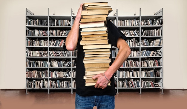 Een jonge man houdt een stapel boeken vast