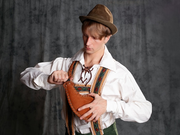 Een jonge man in een nationaal Beiers pak met korte broek op bretels en een hoed