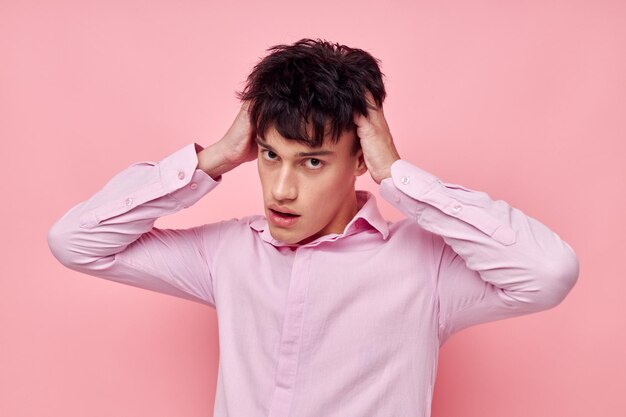 Een jonge man in een roze shirt gebaart met zijn handen een roze achtergrond ongewijzigd