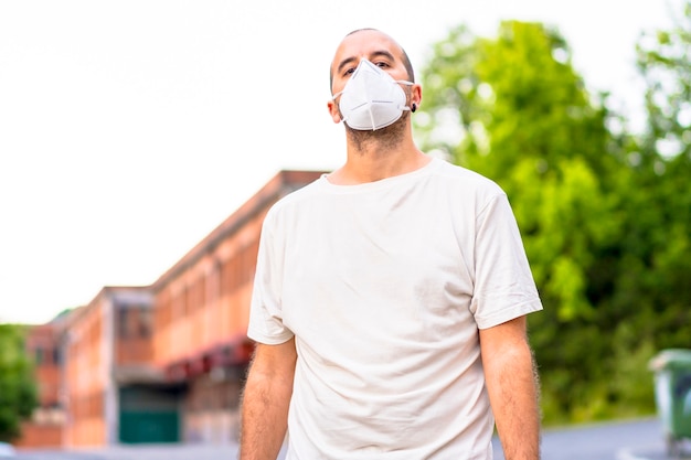 Een jonge man in een wit overhemd en masker poseren in de straat. Coronavirus preventie