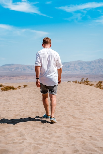 Een jonge man in een wit overhemd loopt door de pittoreske woestijn in Death Valley