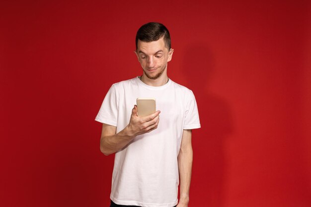 Een jonge man in een wit T-shirt met het Treacher-syndroom houdt een telefoon vast voor mensen met een genetische ziekte met een handicap