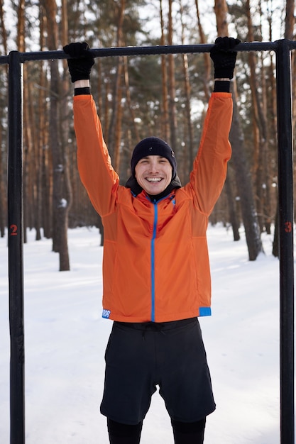 Een jonge man in lichte sportkleding houdt zich bezig met een training op een sportveld op een winterse dag