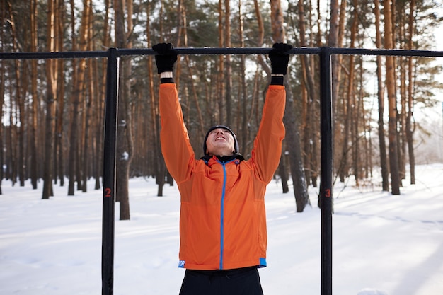 Een jonge man in lichte sportkleding houdt zich bezig met een training op een sportveld op een winterse dag