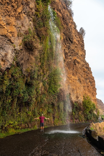 Een jonge man kijkt naar de waterval die valt op de weg genaamd Anjos Waterfall Madeira