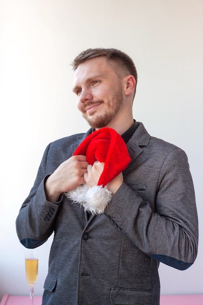 Een jonge man klemt een kerstmanhoed tegen zijn borst en glimlacht.