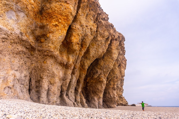 Een jonge man loopt en kijkt naar de prachtige natuurlijke muren van Playa de los Muertos in het natuurpark van Cabo de Gata, Nijar, Andalusië. Spanje