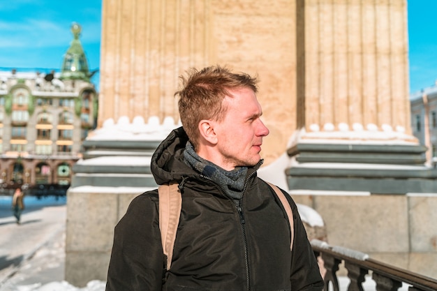 Een jonge man loopt in het centrum van Sint-Petersburg, in de winter langs de Kazankathedraal