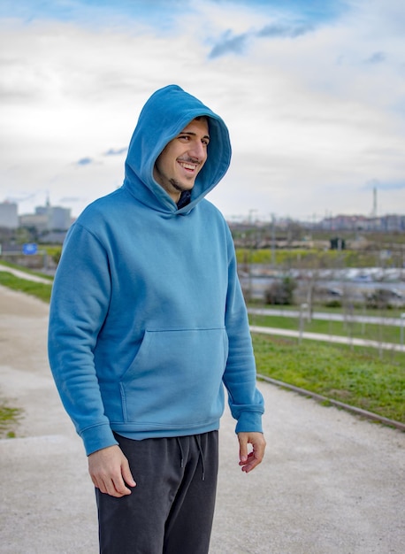 Een jonge man met een blauwe hoodie die glimlacht.
