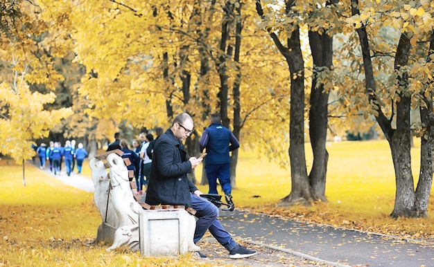 Een jonge man met een bril loopt in het park met een paraplu tijdens de regen.