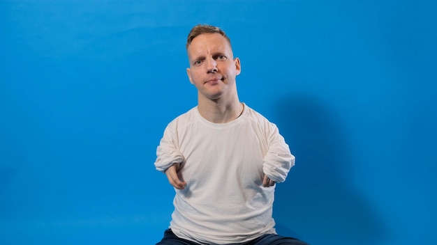 Een jonge man met een handicap zit op een geïsoleerde blauwe achtergrond
