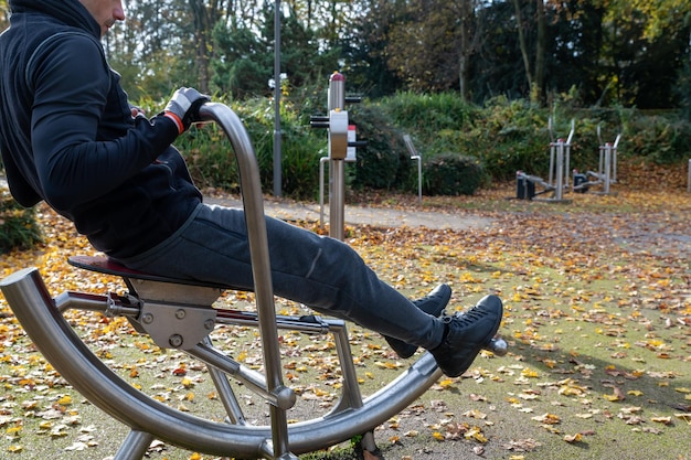 Foto een jonge man oefent buiten in de herfst op de roeimachine.