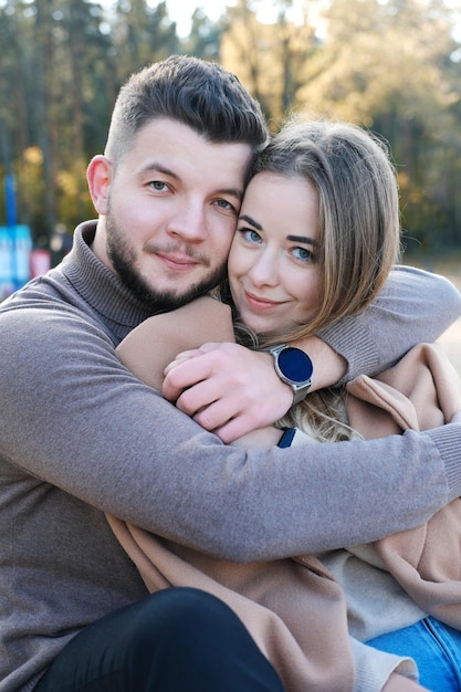 Een jonge man omhelst een vrouw bij de schouders paar camera kijken en glimlachen