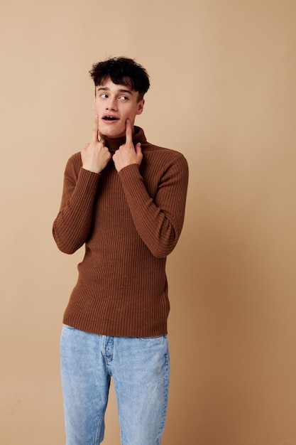 Een jonge man poseren in bruine trui zelfvertrouwen mode lichte achtergrond ongewijzigd