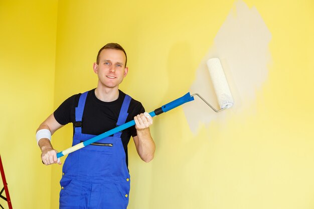 Een jonge man repareert het appartement, oké, schildert de muren opnieuw in een andere kleur