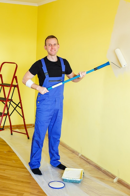 Een jonge man repareert het appartement, oké, schildert de muren opnieuw in een andere kleur