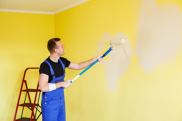 Een jonge man repareert het appartement, oké, schildert de muren opnieuw in een andere kleur