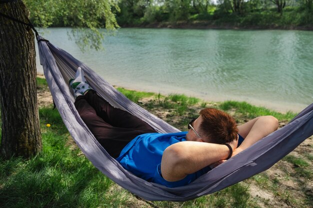 Een jonge man rust in een hangmat aan de oever van de rivier
