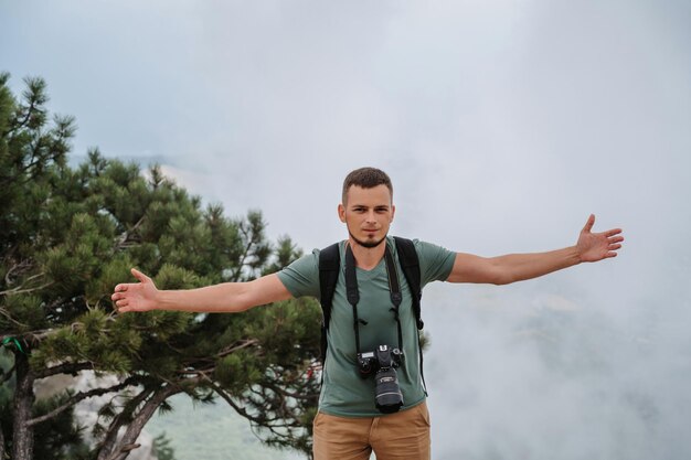 Een jonge man staat met zijn handen omhoog in de frisse lucht in een bergachtig gebied