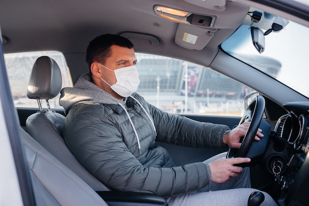 Een jonge man zit achter het stuur en draagt een masker voor persoonlijke veiligheid tijdens het rijden