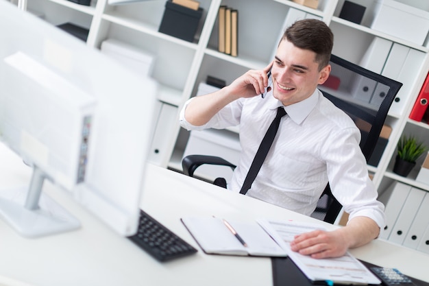 Een jonge man zit op een computer bureau in het kantoor en kijken naar de monitor.