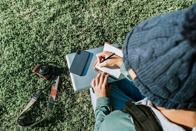 Een jonge mannelijke blogger die in zijn notitieblok schrijft, geniet van het digitale nomadenleven. Concept: werken op afstand