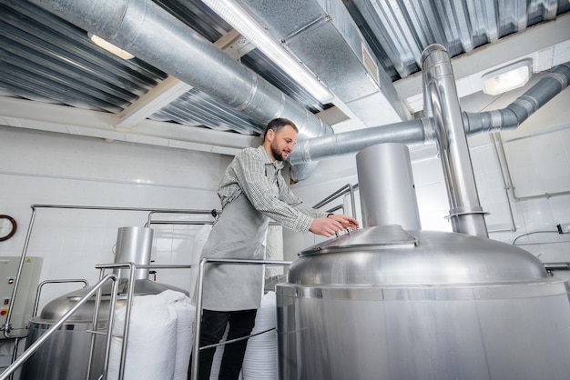 Een jonge mannelijke brouwer giet mout voor bier in een container. Een kleine ambachtelijke brouwerij.