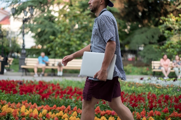 Een jonge mannelijke persoon die de laptop in de stad draagt