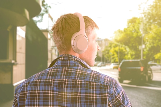 Een jonge mannelijke persoon luistert naar een koptelefoon, geniet van de audio, ontspan en relax