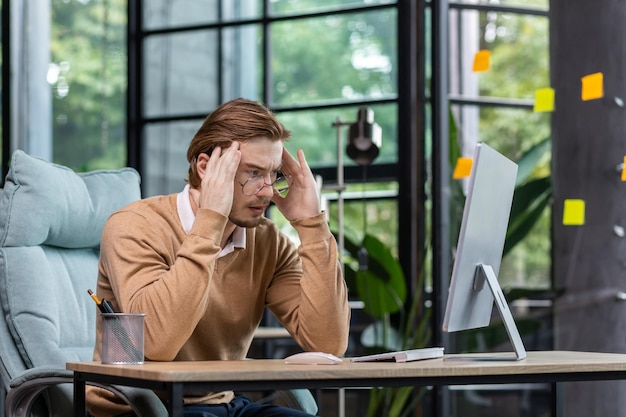 Een jonge mannelijke programmeur, it-ontwikkelaar, denkt na over een nieuw project waar hij geconcentreerd bij zit