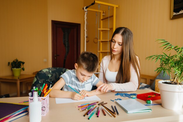 Een jonge moeder doet thuis huiswerk met haar zoon. ouders en training