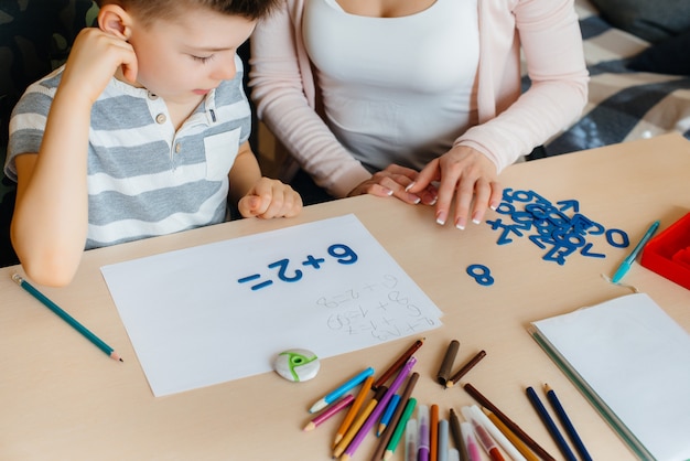 Een jonge moeder doet thuis huiswerk met haar zoon. Ouders en training