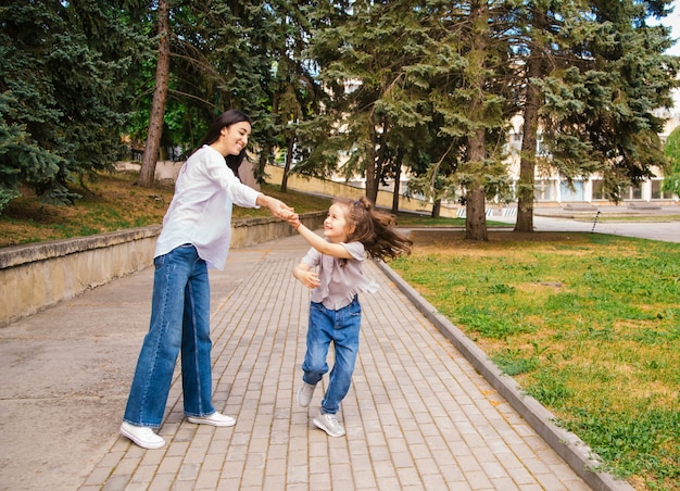 een jonge moeder en haar dochtertje dansen in het park.the concept van een sterk gezin.