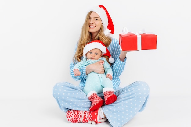 Foto een jonge moeder geeft op eerste kerstdag een geschenk aan een pasgeboren kind