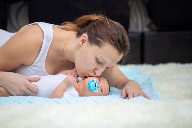 Een jonge moeder kust haar pasgeboren baby