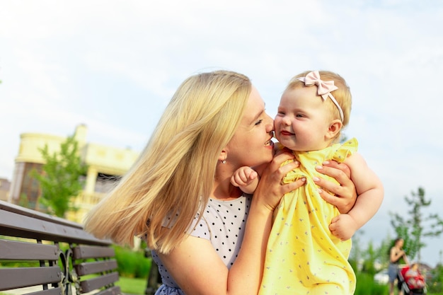 Een jonge moeder loopt met haar baby in het park in de zomer, knuffels en kusjes, gelukkig moederschap
