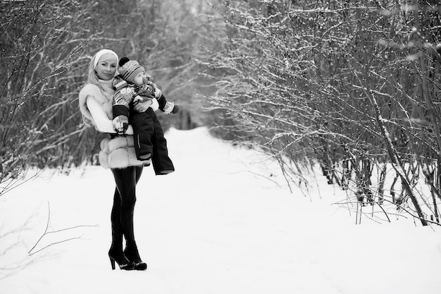 Een jonge moeder loopt op een winterdag met een baby in haar armen in het park