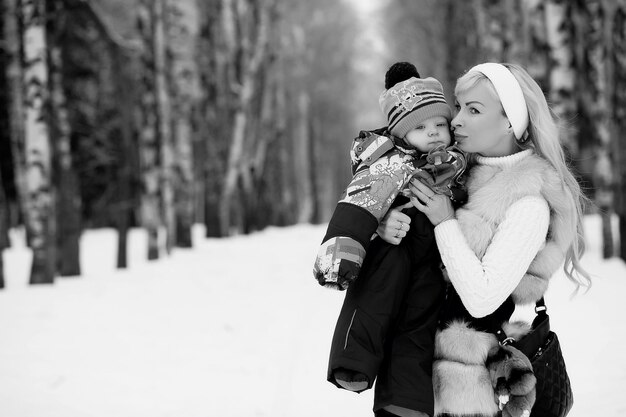 Een jonge moeder loopt op een winterdag met een baby in haar armen in het park