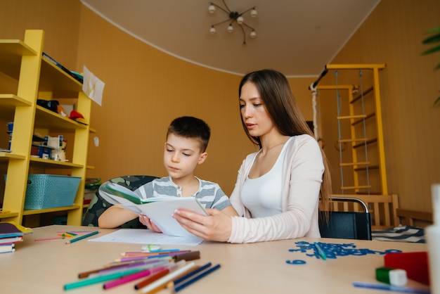 Een jonge moeder maakt huiswerk met haar sonthuis. Ouders en training.