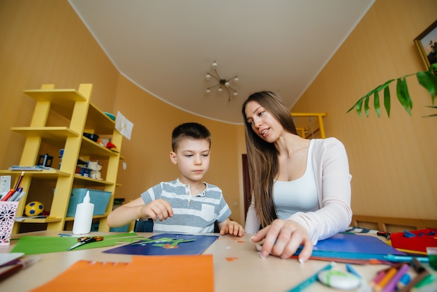 Een jonge moeder maakt thuis huiswerk met haar zoon