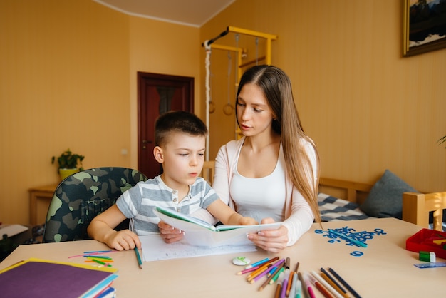 Een jonge moeder maakt thuis huiswerk met haar zoon