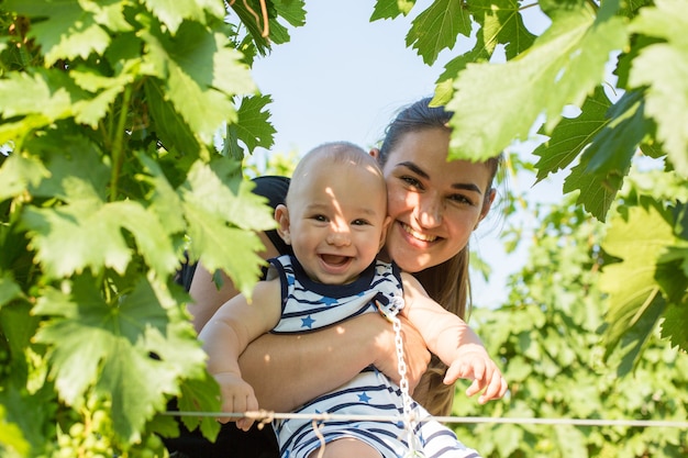 Een jonge moeder met een peuter in een wijngaard in de zomer