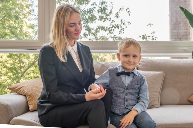 Een jonge moeder met een zoon van vijf jaar zit op de bank en houdt de hand van het kind vast