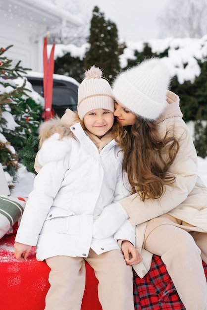 Een jonge moeder met haar dochter in winterkleren Een vrouw kust een kind Het concept van een kerstwandeling in de open lucht