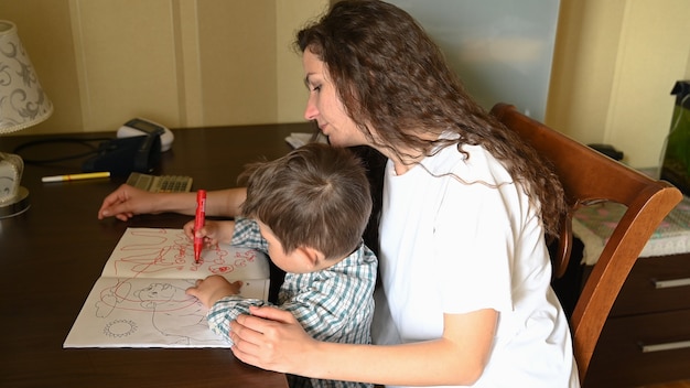 Een jonge moeder schildert met viltstiften met een kind.