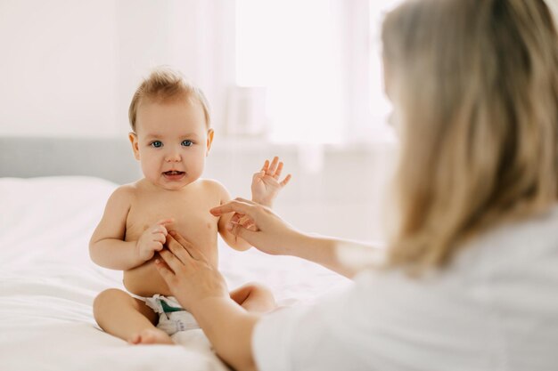 Een jonge moeder smeert de buik van de baby's met babycrème